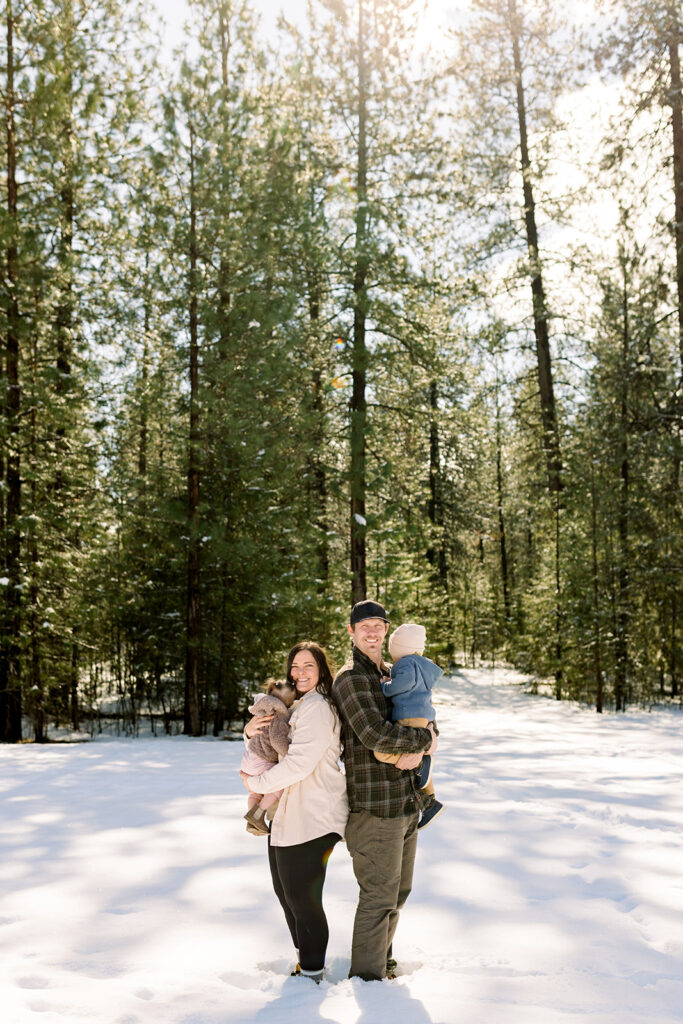 Family embracing in a snowy field with faces turned away during Coeur d'Alene family photographer session